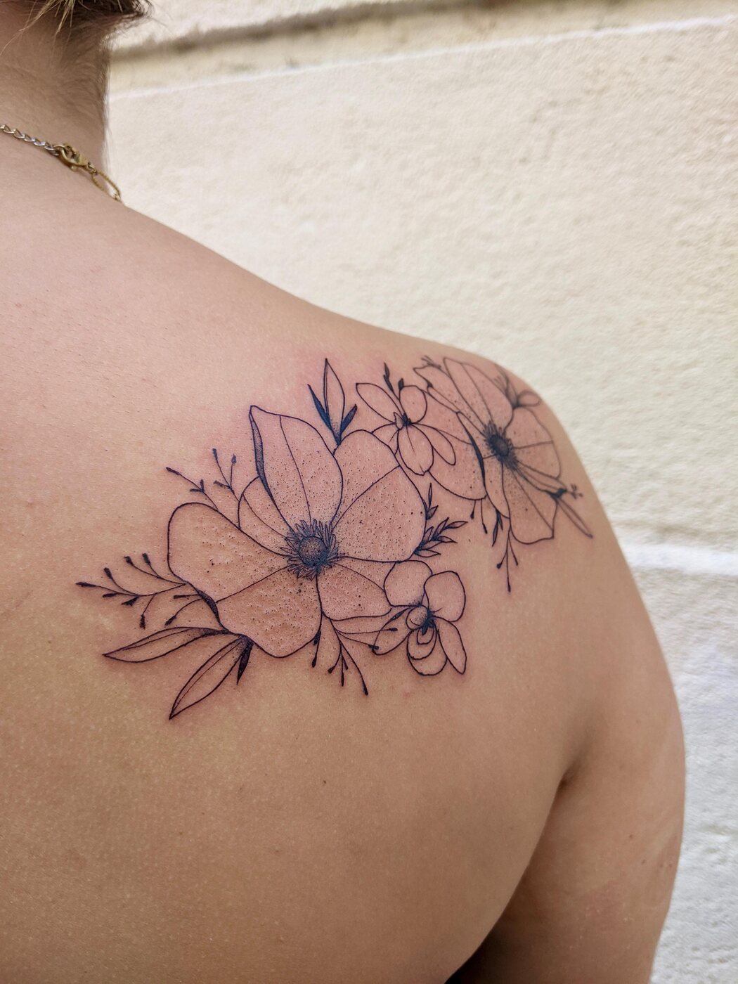 Tatouage fine line, composition florale sur l'épaule